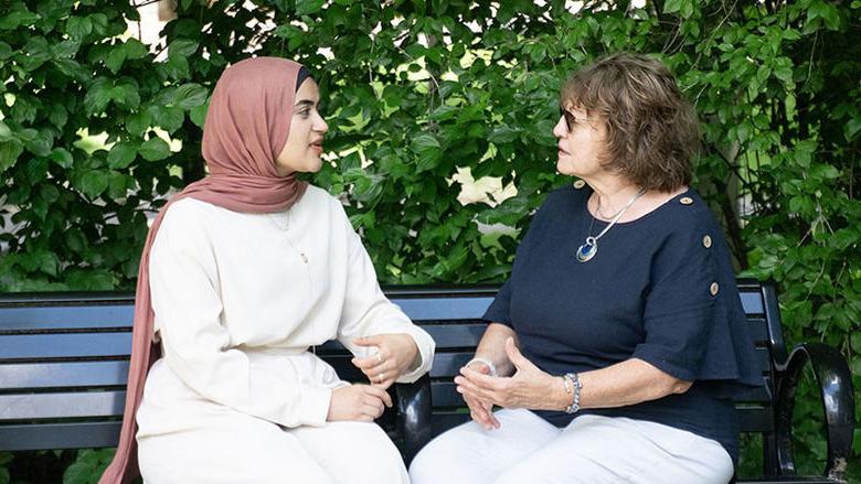 Two women sitting on a bench talking